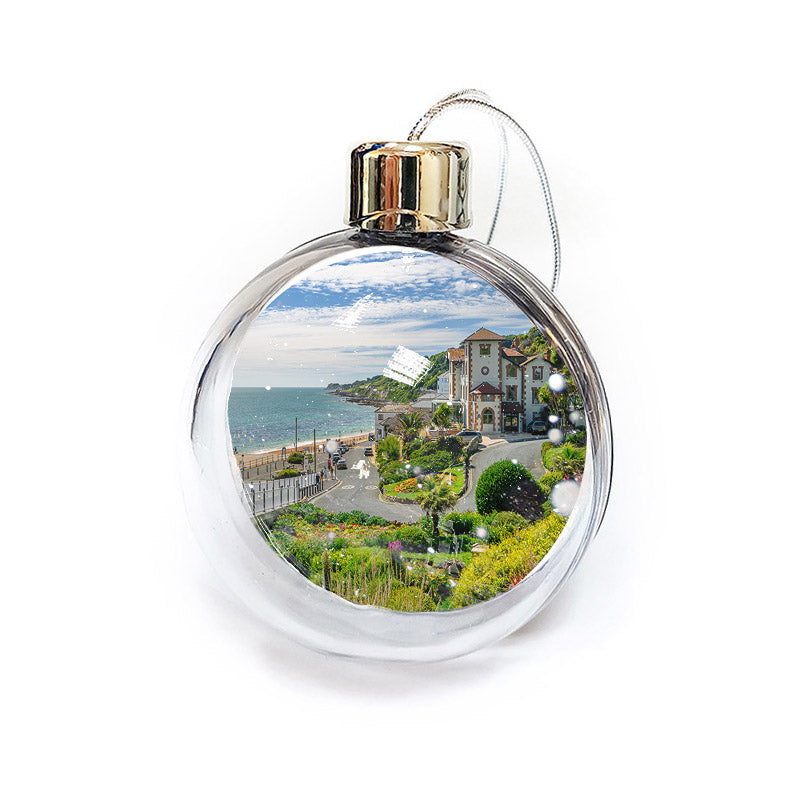 The Ventnor bauble by Available Light Photography features a scenic view of a coastal town, capturing detailed depictions of buildings, lush greenery, and the ocean within its clear glass casing.