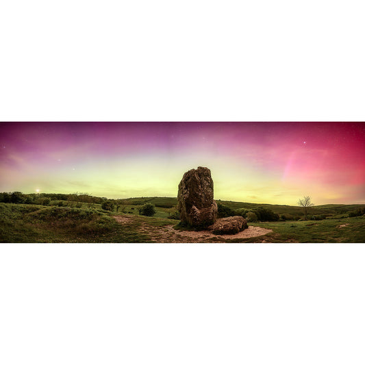 Landscape view featuring a large standing rock formation under a colorful sky transitioning from pink to green hues, with grassy hills and sparse vegetation in the background. Image number: 2866. Product Name: The Northern Lights, The Longstone Brand Name: Available Light Photography