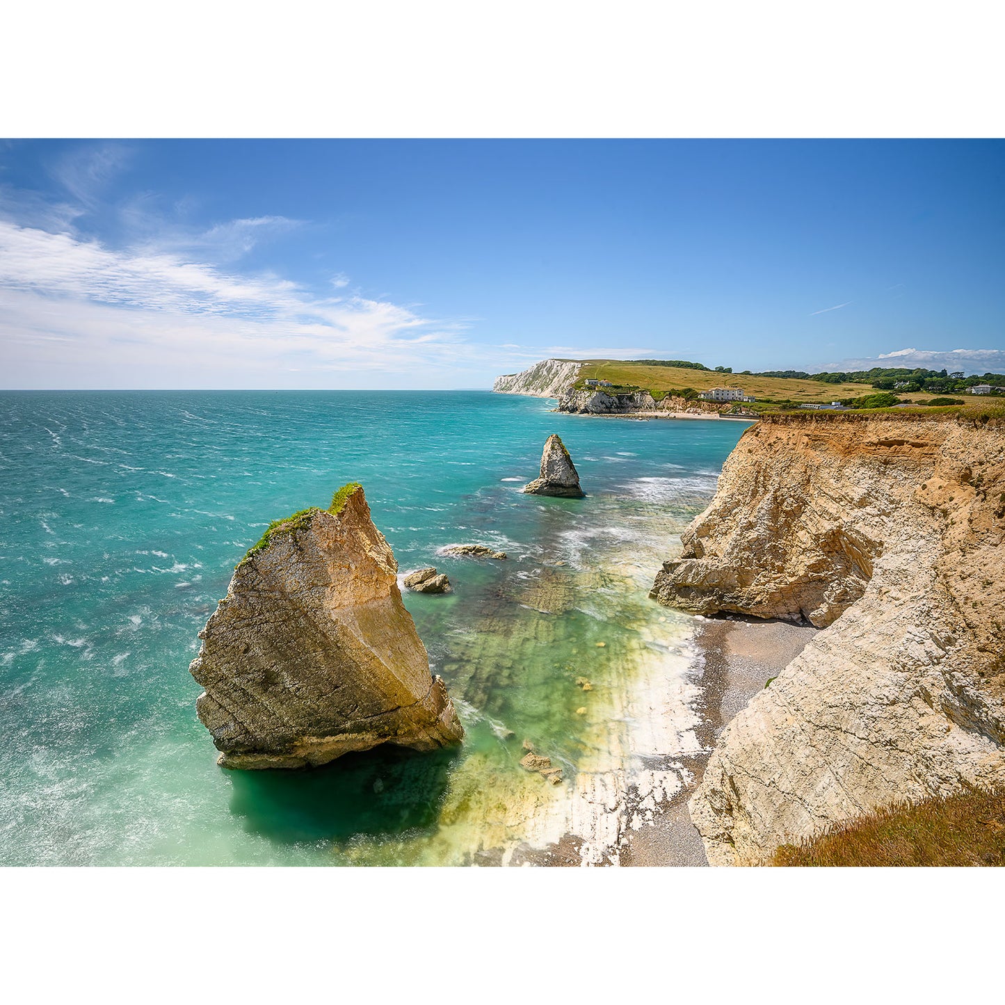 Coastal landscape with turquoise water, jagged rock formations, and white cliffs under a blue sky. For more details, refer to Freshwater Bay by Available Light Photography.