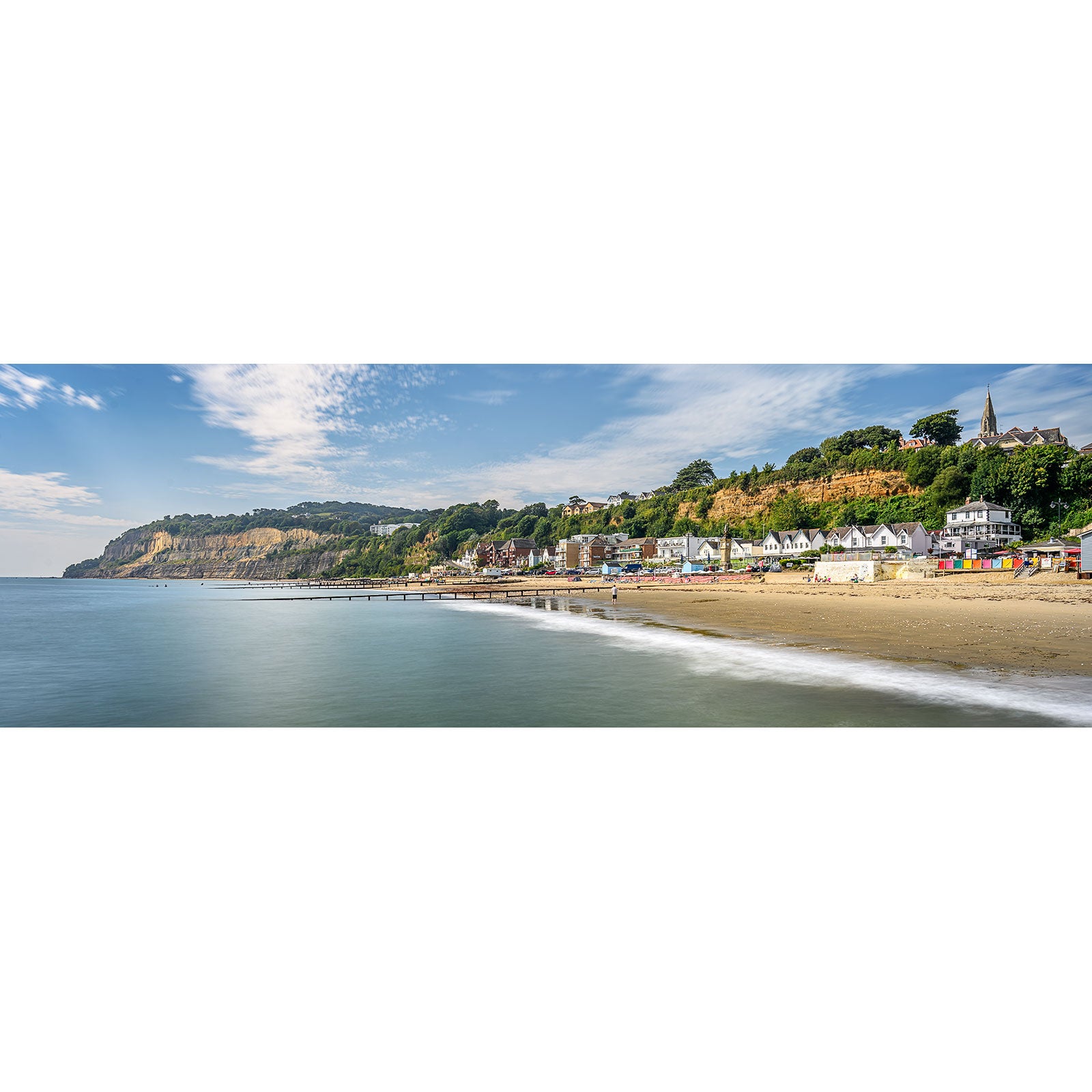 Shanklin by Available Light Photography captures a panoramic view of a coastal town, image number 2153, lined with houses along the beach, a cliff in the background, and the calm sea extending to the horizon under a partly cloudy sky.