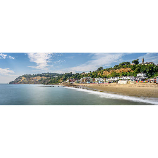 Shanklin by Available Light Photography captures a panoramic view of a coastal town, image number 2153, lined with houses along the beach, a cliff in the background, and the calm sea extending to the horizon under a partly cloudy sky.