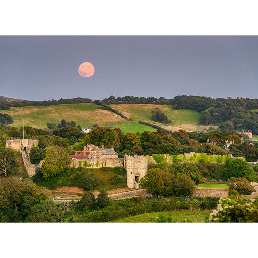 A large moon rises over Carisbrooke Castle, surrounded by green fields and trees, with a twilight sky in the backdrop; Image number: 2926 from Available Light Photography's "Moonrise" collection.