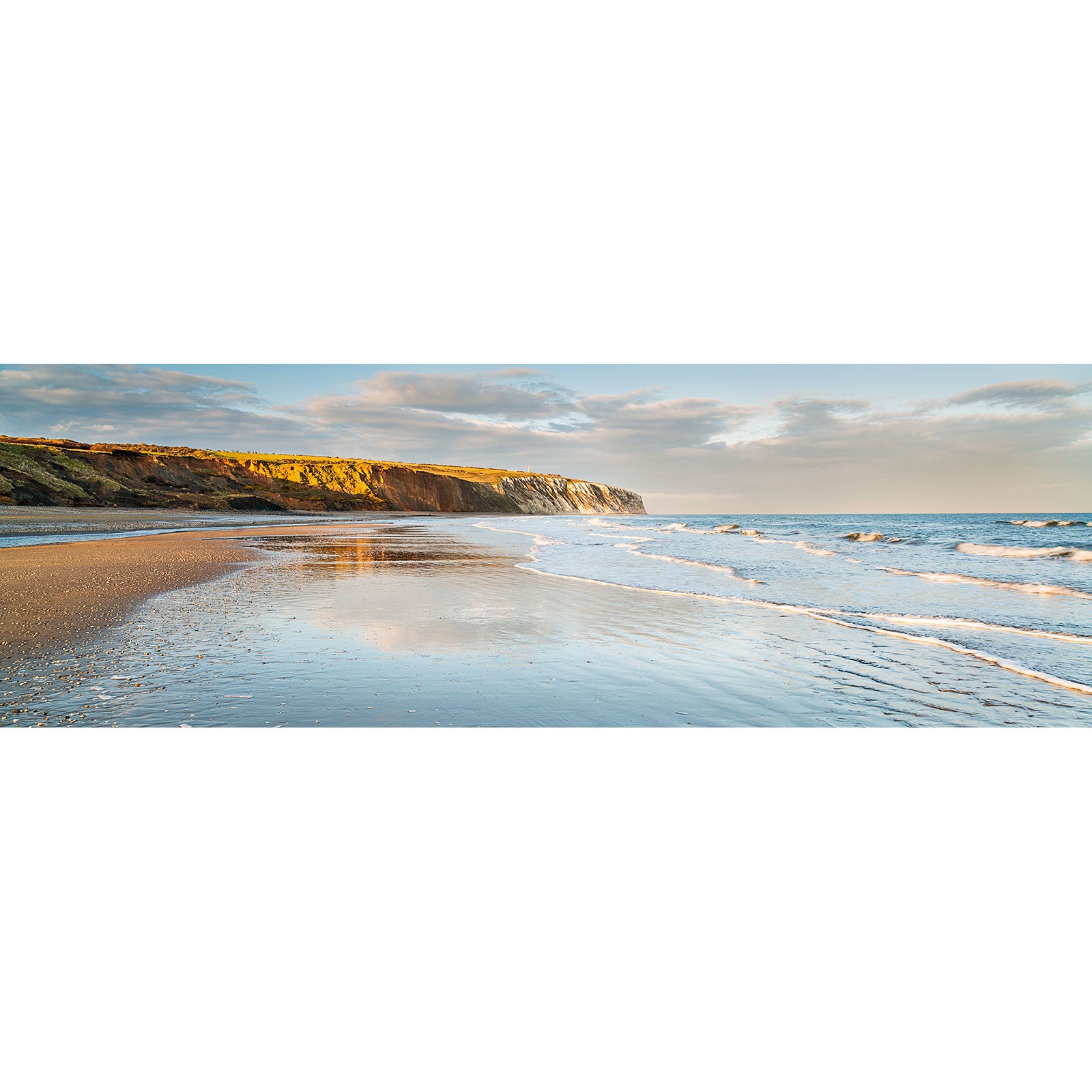 Golden sunlight illuminates Culver Cliff seaside cliffs as gentle waves wash onto a sandy beach by Available Light Photography.