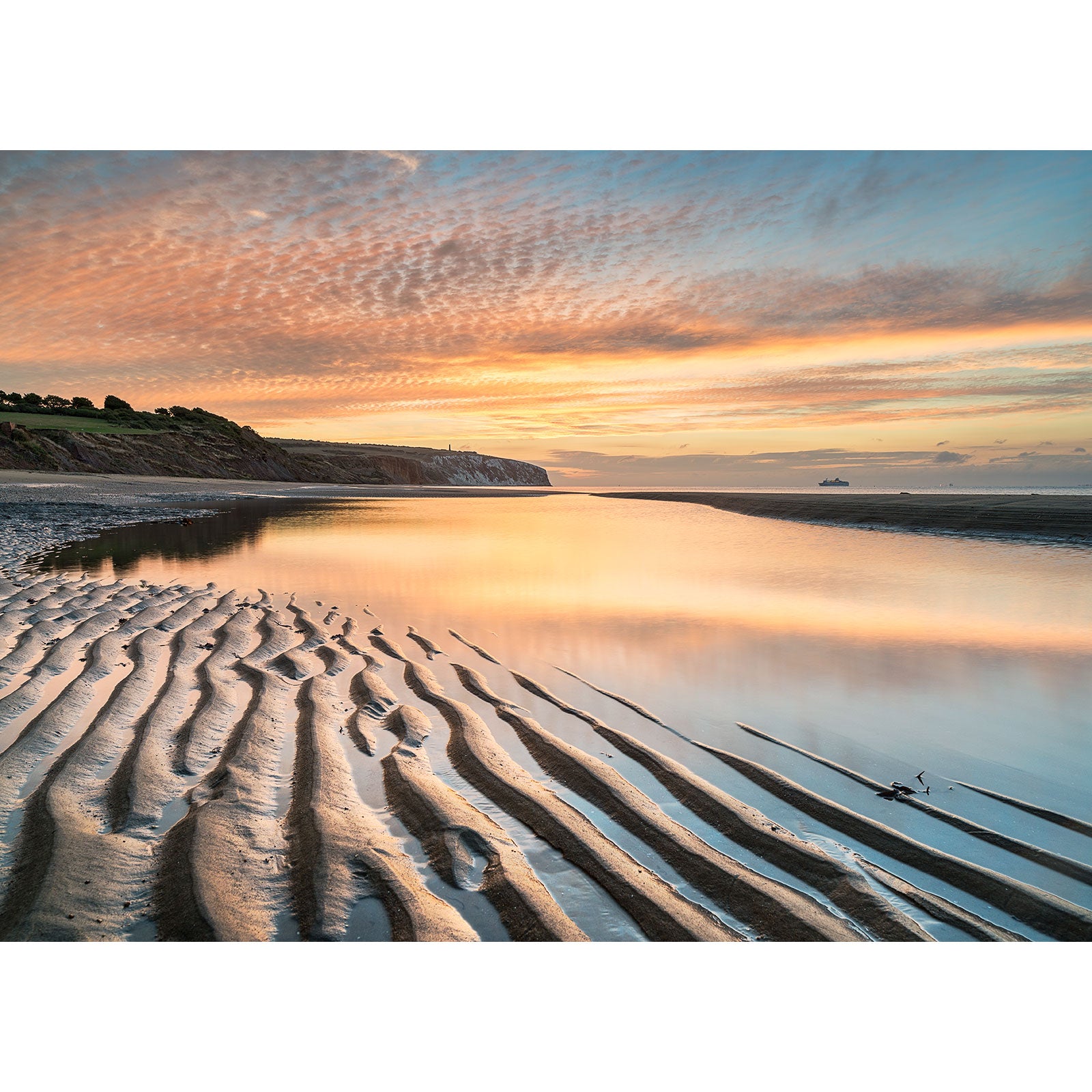 Rippled sand at low tide reflecting a vibrant sunset sky with clouds, reminiscent of a Culver Cliff composition by Available Light Photography.