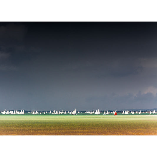 A fleet of Round the Island Race sailboats racing under a stormy sky off the Isle of Wight captured by Available Light Photography.