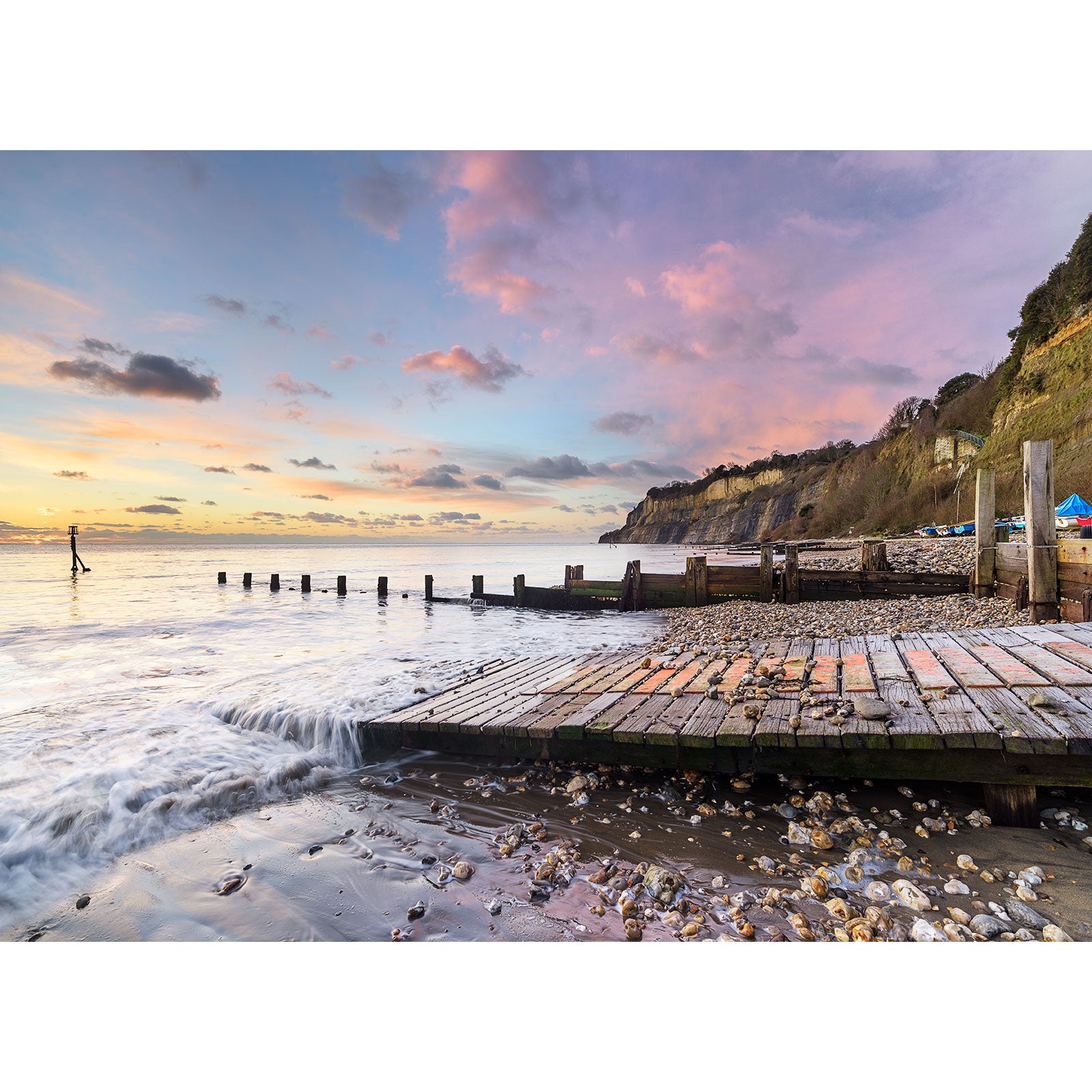 Shanklin Beach pier leading into the Isle of Wight sea with a person standing in the shallow water at sunset captured by Available Light Photography.