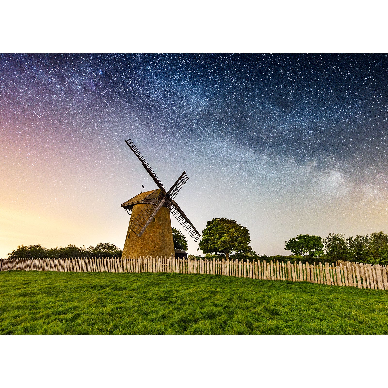 A Milky Way night sky over a Bembridge Windmill surrounded by a wooden fence on the Isle of Wight captured by Available Light Photography.