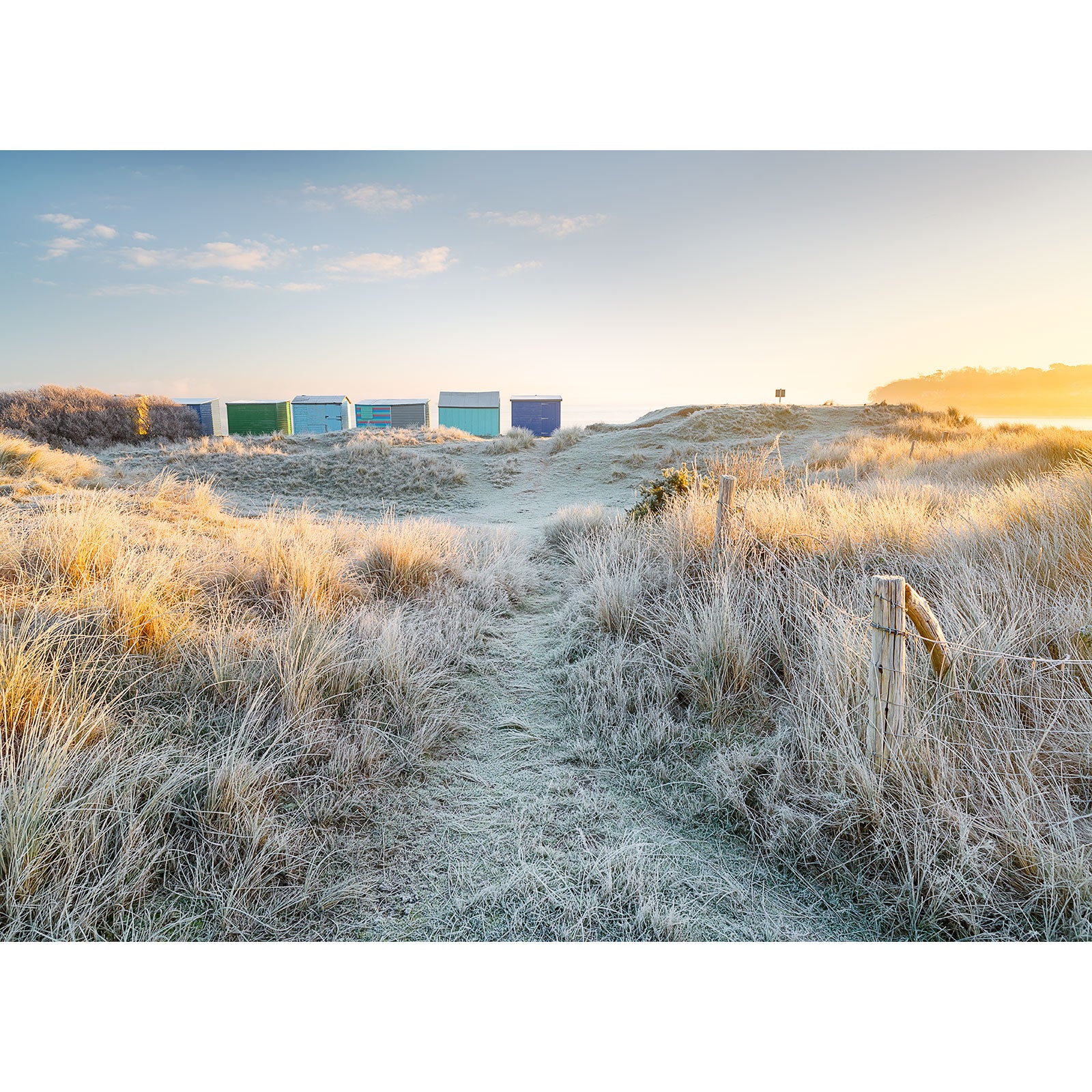 Row of beach huts on a sandy dune at sunrise with Frosty Morning, The Duver by Available Light Photography.