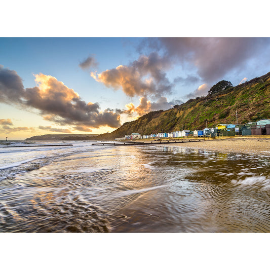 Sunset over a peaceful Lake Beach on the Isle of Wight with colorful beach huts and gentle waves by Available Light Photography.