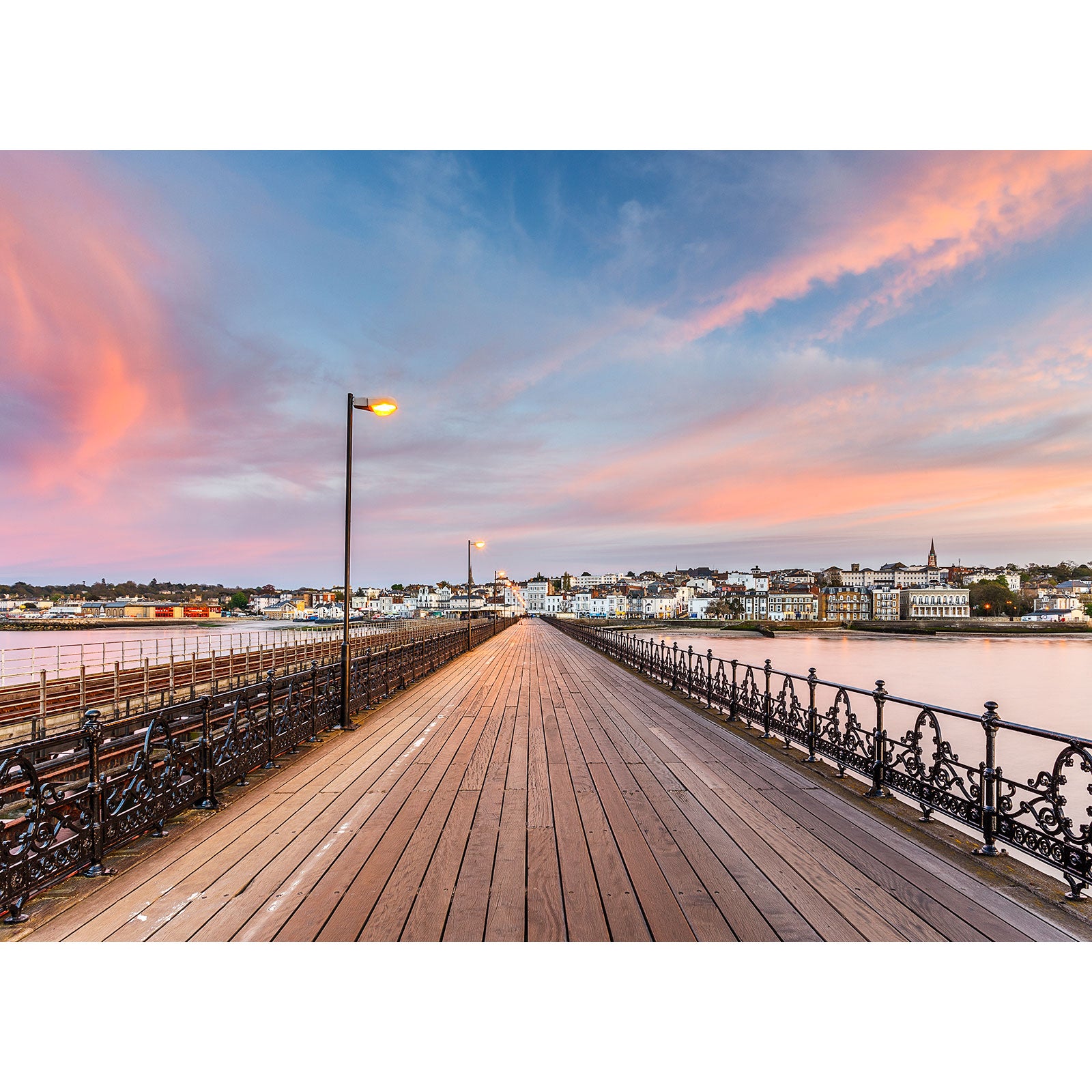 Ryde Pier leading to a coastal town on the Isle of Wight against a colorful sunset sky, captured by Available Light Photography.