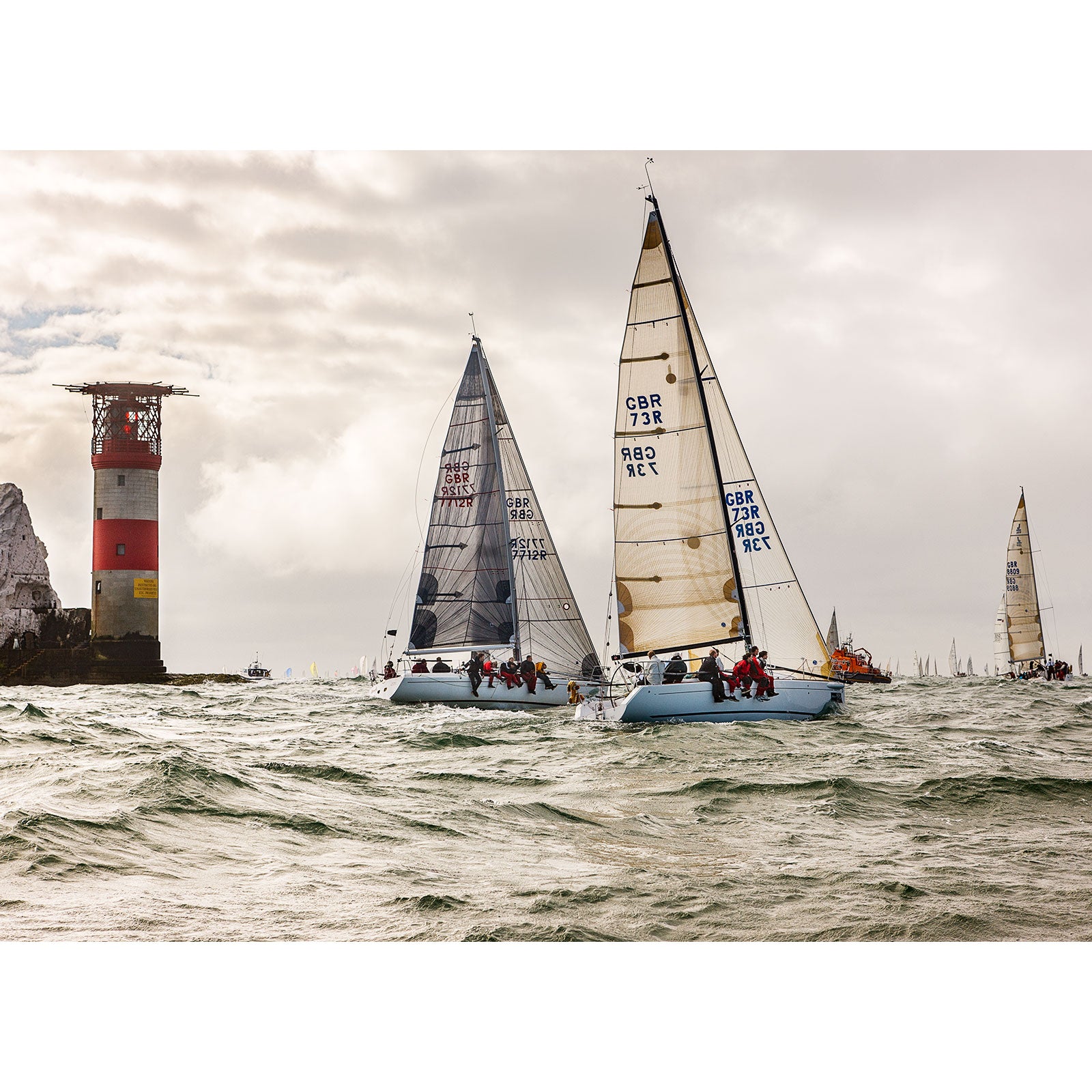 Sailboats racing near a lighthouse on the choppy sea off the Isle of Wight under a cloudy sky, captured by Available Light Photography during the Round the Island Race.