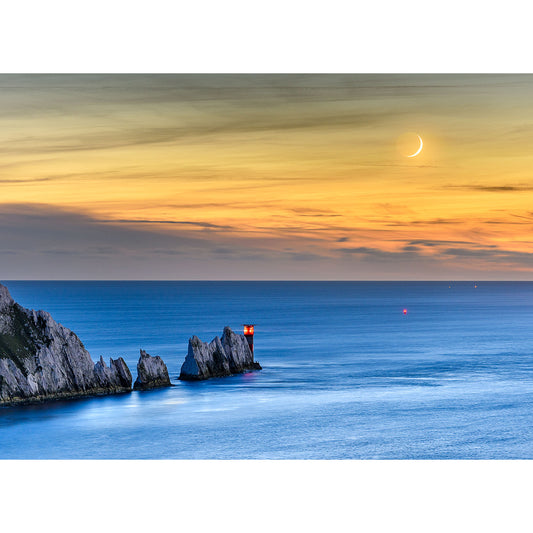 Crescent moonset over The Needles over a coastal landscape at twilight with illuminated rocky outcrops and calm sea near Gascoigne Isle captured by Available Light Photography.