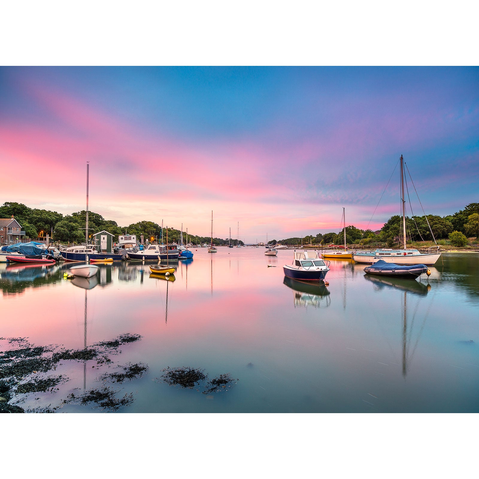 Wootton Creek boats moored in a serene harbor at dusk with a colorful sky reflection on the water on the Isle of Wight, by Available Light Photography.