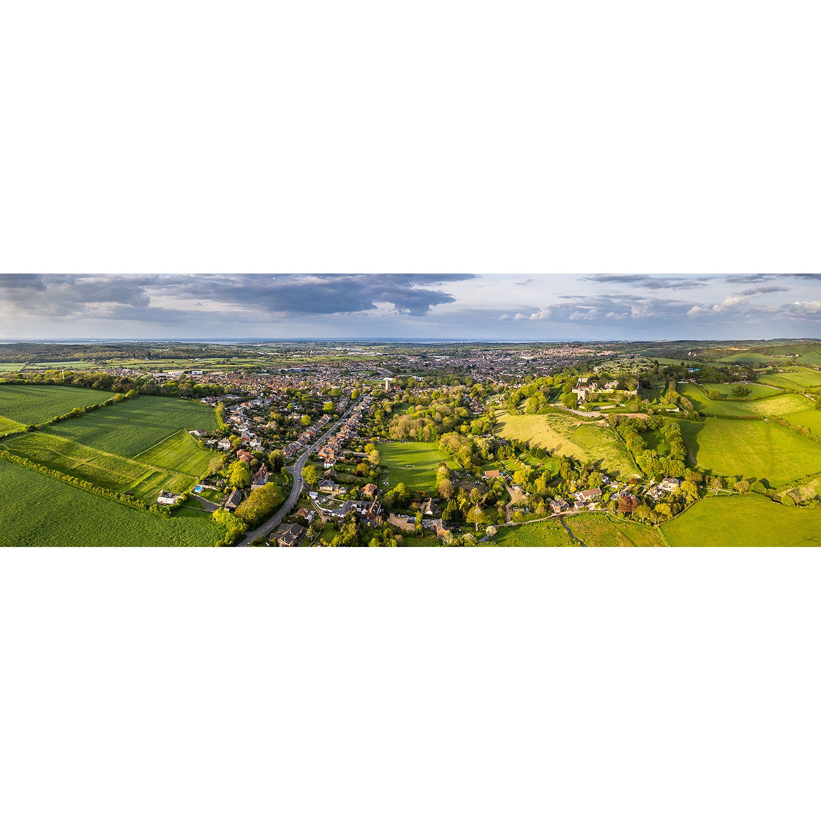 Aerial view of Carisbrooke with surrounding green fields and distant clouds on the Isle of Wight by Available Light Photography.