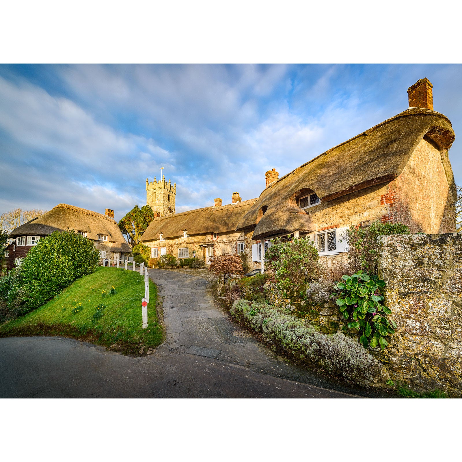 Traditional thatched cottages with a Godshill Church tower in the background in an English village, captured perfectly by Steve Wight of Available Light Photography.