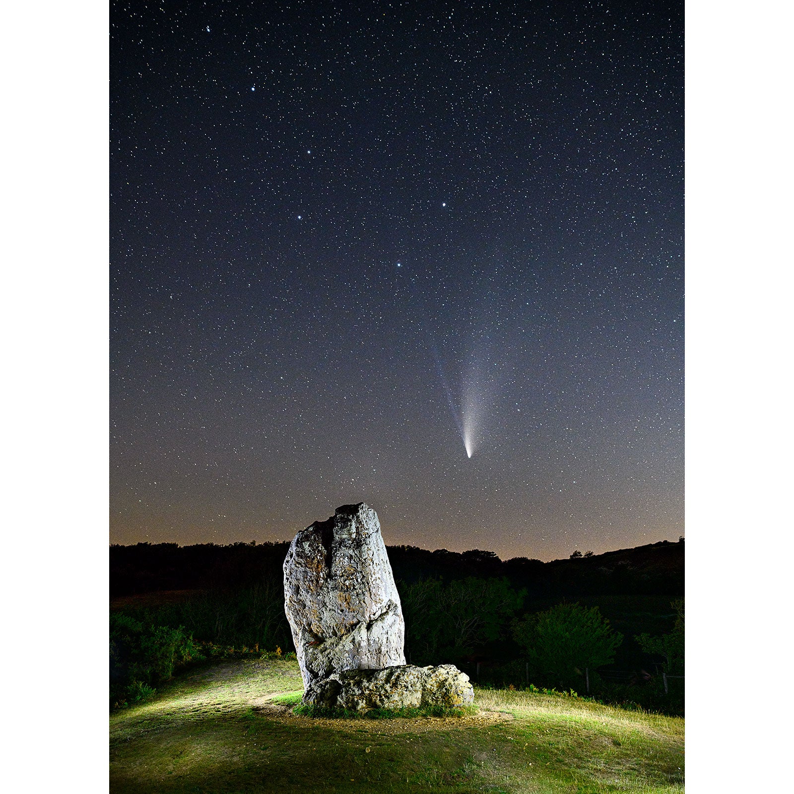 A Comet Neowise visible in a starry night sky above a solitary boulder on the Isle of Wight by Available Light Photography.