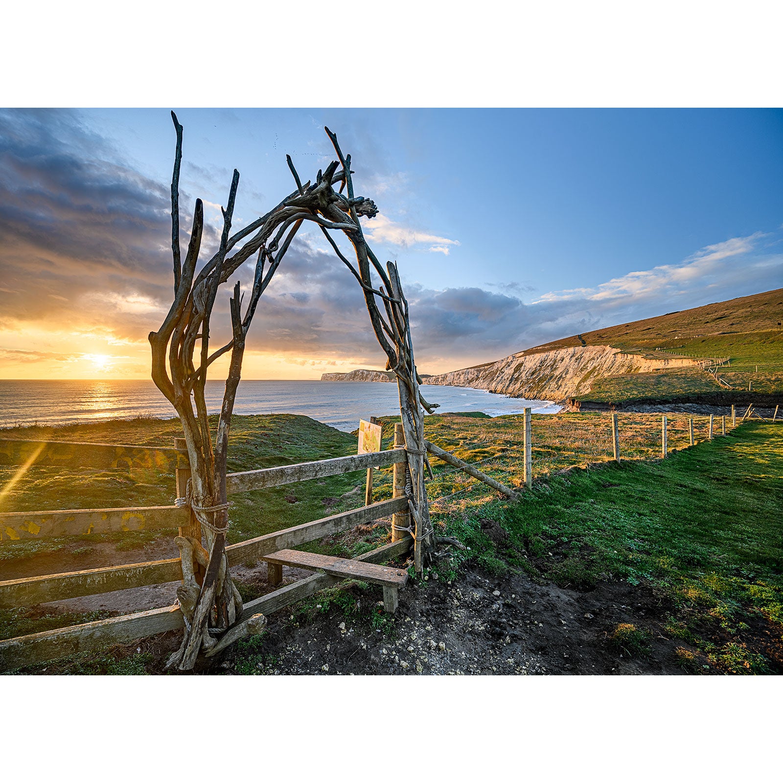 A Compton Bay wooden archway frames a coastal sunset with cliffs in the distance on the Isle of Wight by Available Light Photography.