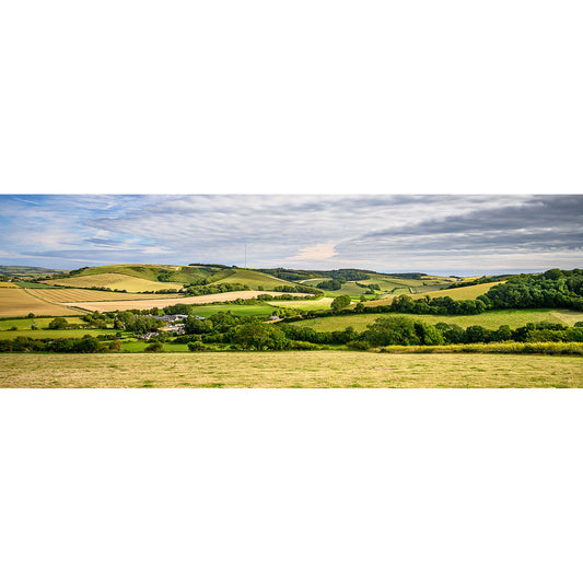 Rolling hills with patchwork fields and a small village nestled in the Bowcombe Valley under a partly cloudy sky on the Isle of Wight, captured by Available Light Photography.