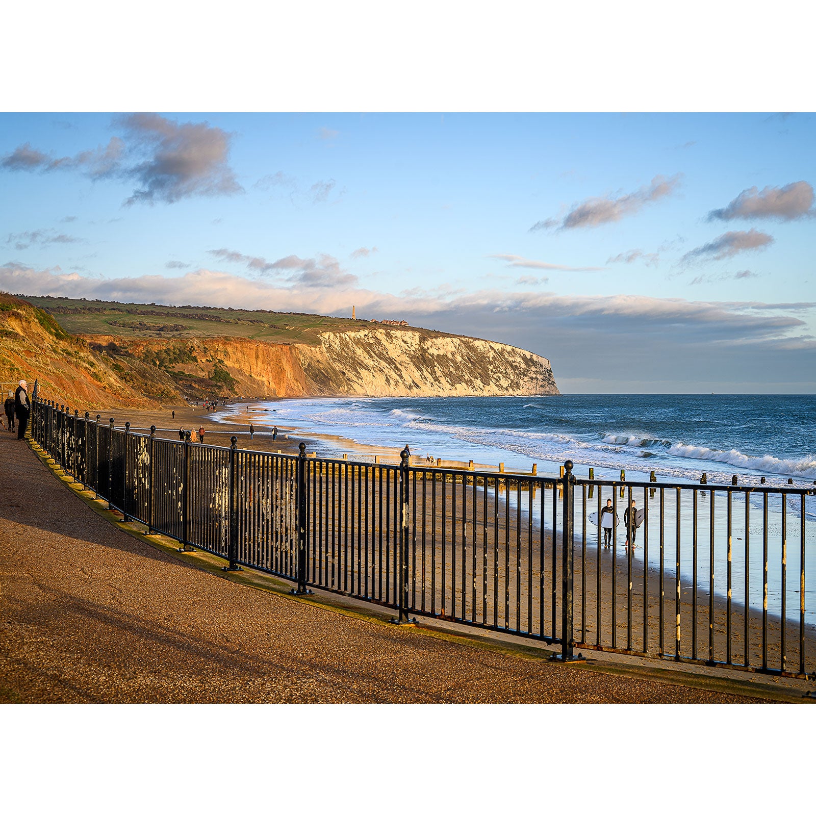 An oceanside walkway with a metal railing, overlooking Culver Cliff beach with cliffs in the distance on the Isle of Wight during golden hour. - Available Light Photography